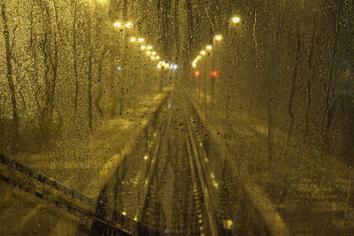 Illuminated street lights seen through wet glass