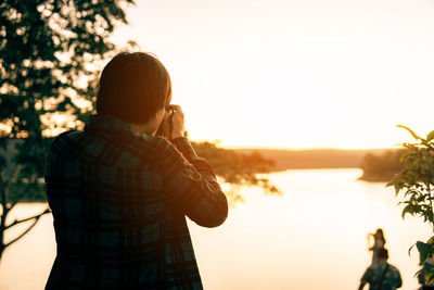 Rear view of woman standing against sky during sunset