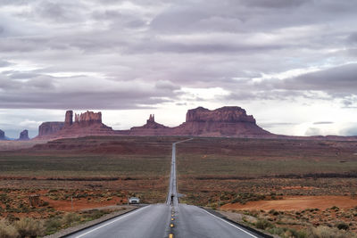 Road passing through landscape against cloudy sky