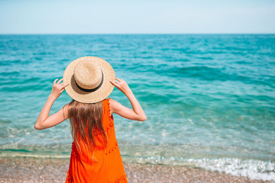 Woman wearing hat on beach against sky