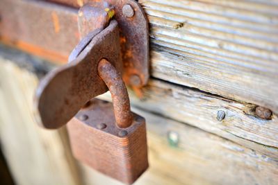 Close-up of old padlock on rusty metal over wood