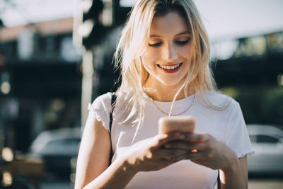 Smiling young woman using mobile phone outdoors