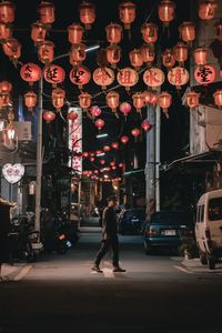 Full length of woman walking on illuminated street at night