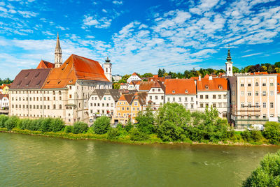 Buildings by river against sky