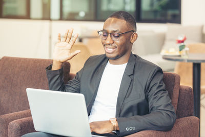 A black man works on a tablet computer in the hotel lobby.