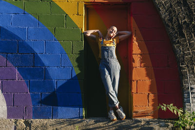 Smiling non-binary person standing in front of door