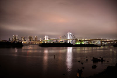 Illuminated rainbow bridge over tokyo bay against sky at dusk