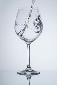 Close-up of water falling in wineglass against white background