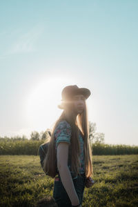 Woman wearing hat standing on field against sky