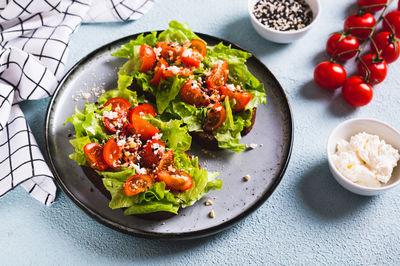 Sandwich with tomatoes and lettuce on rye bread on a plate on the table