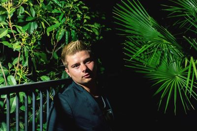 Portrait of young man standing against trees