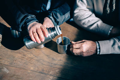 Midsection of man holding coffee cup on table