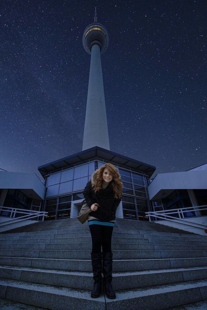 FULL LENGTH PORTRAIT OF SMILING WOMAN STANDING AGAINST SKY AT NIGHT