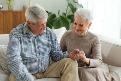 Portrait of senior couple sitting on sofa at home