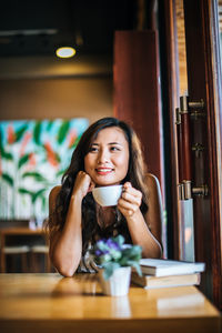 Portrait of smiling young woman sitting at restaurant