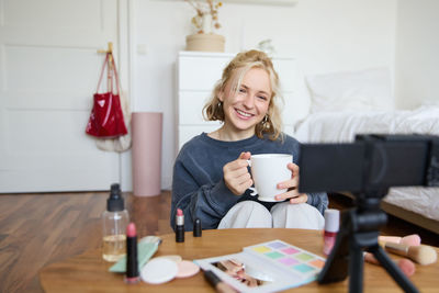 Young woman using mobile phone while sitting on table