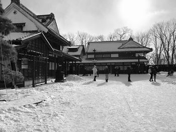 People on snow covered field by house