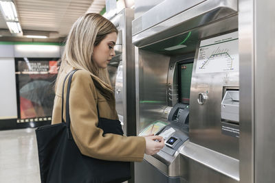 Woman with purse paying with credit card and buying ticket at station