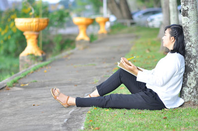 Side view of woman sitting on grass