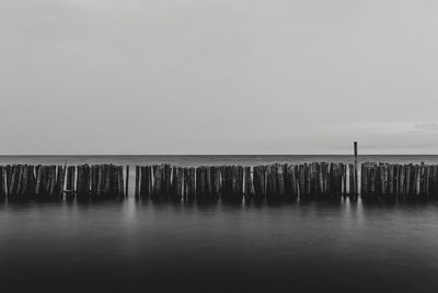 Wooden posts in sea against clear sky