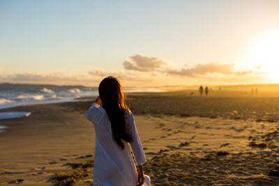 Rear view of woman standing at beach