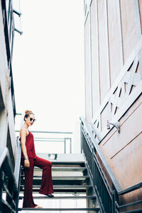 Low angle view of young woman standing on steps against clear sky