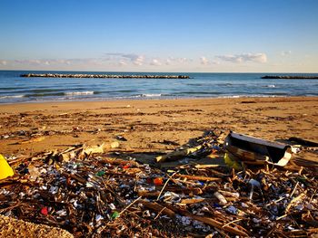 Garbage on beach by sea against sky