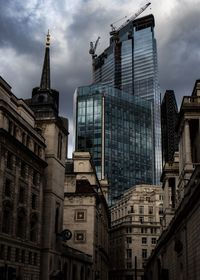 Low angle view of buildings in city against cloudy sky