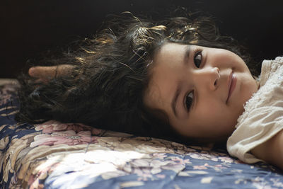 Portrait of cute girl lying on bed at home