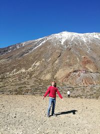 Full length of boy standing on desert against snowcapped mountains