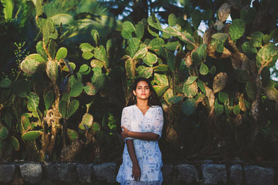 Portrait of young woman standing against plants