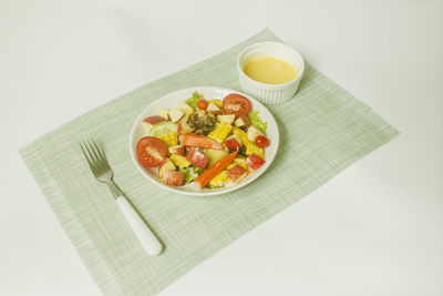 Mixed fruit and vegetable salad with crab stick dressing on white background