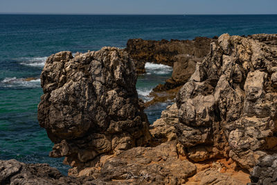 Rock formation on beach against sky