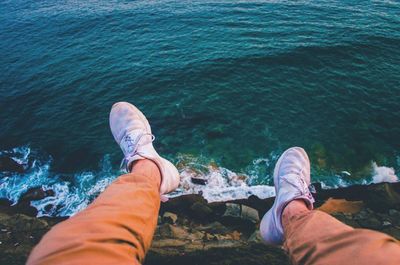 Low section of man sitting by sea