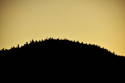 Silhouette trees on landscape against clear sky during sunset