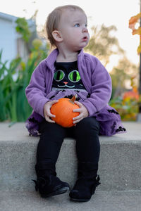Full length of girl looking away while holding pumpkin on land