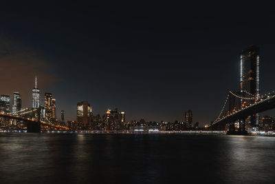 Illuminated bridges over river in city at night