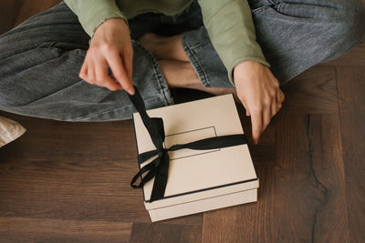 Close-up of female hands opening a gift box with a bow