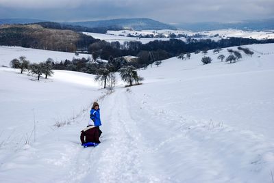 Rear view of girl walking on snow covered road during winter