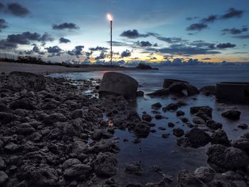 Rocks on beach against sky during sunset