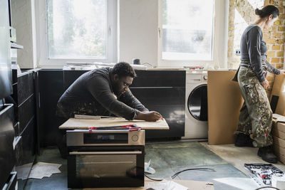 Male and female carpenter working in kitchen at home