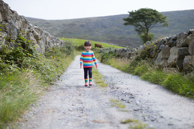 Front view of girl walking on footpath by road