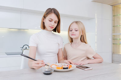 Portrait of smiling friends using mobile phone while sitting at home