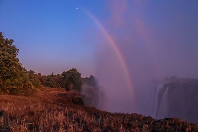 Scenic view of rainbow over landscape against sky