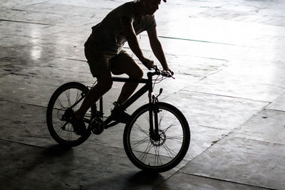 Low section of man riding bicycle on road