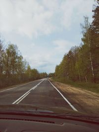 Road by trees against sky seen through car windshield