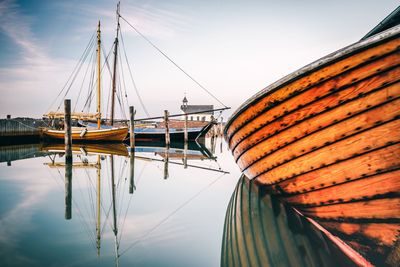 Sailboats moored at harbor against sky