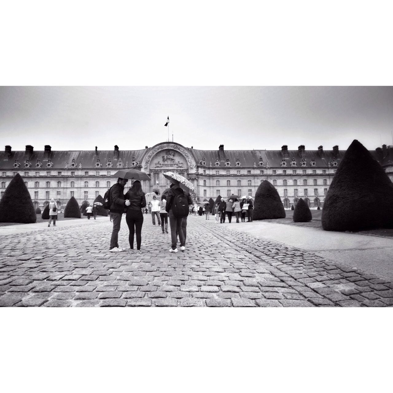 architecture, built structure, walking, clear sky, building exterior, copy space, men, the way forward, person, cobblestone, lifestyles, day, full length, sky, in a row, transfer print, sunlight, outdoors, arch