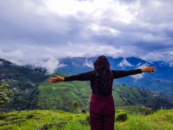 Girl in victory pose at mountain top with dramatic sky at morning