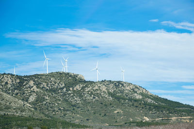 Wind turbines on land against sky